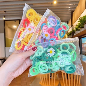 Handheld view of colorful elastic hair bands in floral zip-lock bags for girls