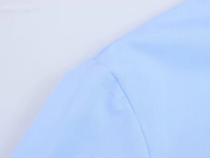 Gros plan sur les coutures soignées et la texture fine d'une chemise bleu clair