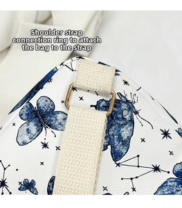 Macro detail of golden D-ring connector and beige strap on butterfly pattern backpack