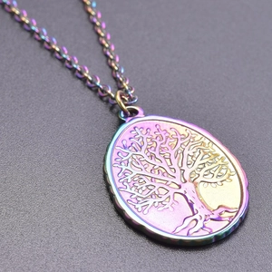 Detail of a rainbow stainless steel oval pendant featuring an engraved Tree of Life design