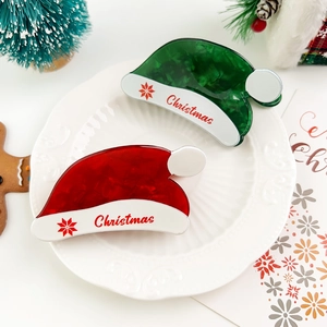 Close-up of red and green Christmas hat hair claws with marble texture in festive setting