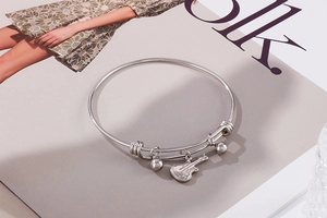 Close-up of adjustable silver stainless steel bracelet with guitar and bead charms