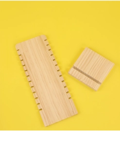 Macro view of natural wood DIY weaving tool set with grooved base on yellow background