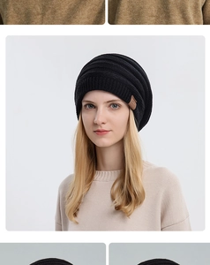 Close-up of black ribbed knit beanie featuring a brown leather label with stitch details