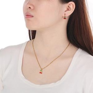 Primo piano di un modello che indossa un set di collana e orecchini a ciliegia rossi