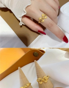 Close-up of golden bow-knot ring with matte finish texture on a wooden display