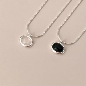 Macro detail of oval black agate and white gemstone pendants on silver chains