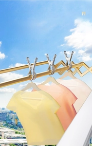 Golden stainless steel windproof clips on rack set against a clear blue sky background