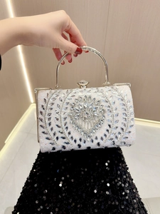 Close-up of luxury evening clutch featuring radiant rhinestone flower patterns and metal handle