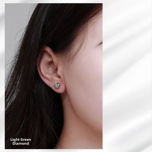 Close-up of a model wearing a light green moissanite stud earring with silver four-prong setting