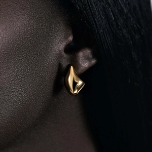 Macro shot of 18k gold teardrop earrings with a modern streamlined geometric design