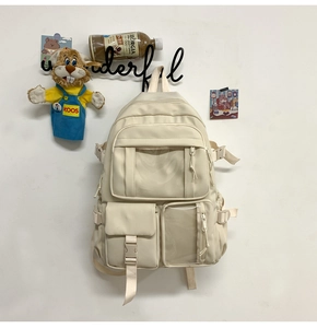 Dettaglio di uno zaino campus crema con design funzionale multitasche sulla parete