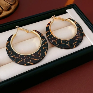 Macro shot of large leopard print hoop earrings in a black jewelry box for women