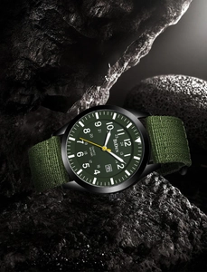 Military watch detail with olive green dial and nylon strap on rugged black stone