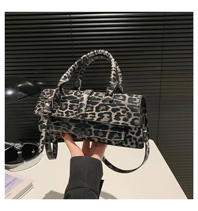 Close-up of leopard print crossbody bag featuring glossy PU texture and belt buckle detail