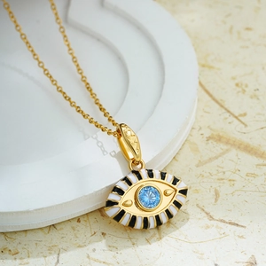 Macro shot of gold evil eye pendant with blue center stone and enamel detailing