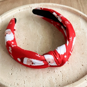Detail of red Christmas headband featuring Santa Claus prints and knotted fabric design