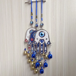 Vintage Hamsa Hand and Evil Eye wall hanging ornament with blue bells on wood background