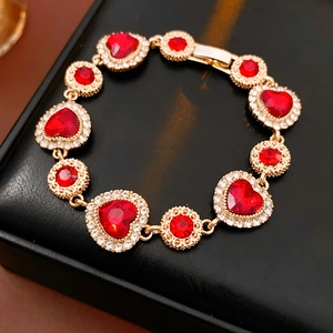 Dettaglio di un bracciale vintage dorato con gemme rosse a cuore e piccoli diamanti decorati
