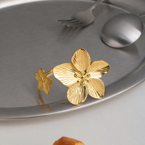Dettaglio del bracciale a fiori dorato 18K con petali testurizzati su vassoio in metallo