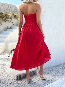 Rear view of long red halter neck maxi dress with flowing fabric on white steps