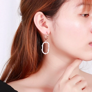 Gros plan de boucles d'oreilles ovales en or rose avec zircons blancs sur modèle