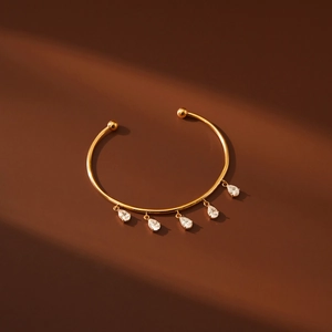 Detail of 18k gold plated cuff bracelet with five hanging pear-cut zircon stones
