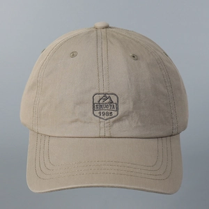 Close-up of the khaki cotton baseball cap featuring detailed mountain shield embroidery