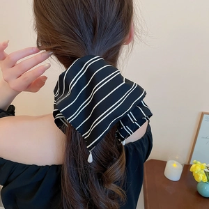 Détail de pince à cheveux avec tissu rayé noir et blanc et pendentif perle sur les cheveux