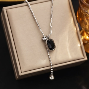 Macro detail of asymmetric beaded silver chain necklace with black zircon pendant