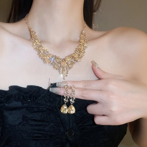 Close-up of gold V-shaped necklace and drop earrings with yellow teardrop crystals