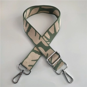 Detail of green cotton bag strap with beige geometric patterns and silver metal hooks