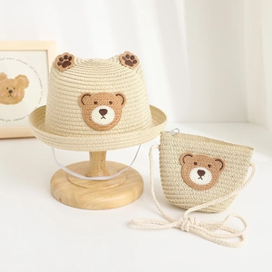 Close-up of baby straw hat and matching bag set with cute bear embroidery and ears