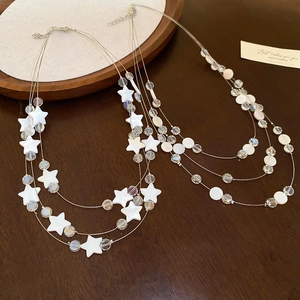 Détail du collier de coquillages en étoile et cercle sur un plateau en bois rustique