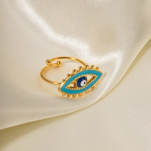 Detail of 18K gold-plated evil eye ring with blue enamel on white silk fabric background