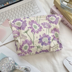 Detail of floral makeup bag with metal zipper and purple blossom print on desktop