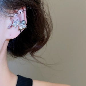 Detailed view of silver bow ear cuff with clear zircon and dark grey pearl on model