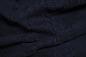 Macro shot of navy blue knit sweater with twisted cable pattern and thick yarn texture