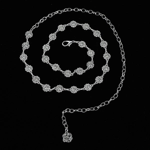 Close-up of silver metal waist chain featuring intricate hollow flower links and rose pendant