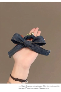 Vue détaillée du chouchou en denim bleu foncé avec un nœud et une boucle cœur en métal