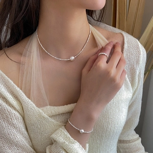 Close-up of elegant pearl necklace and bracelet set with silver chain on model neck