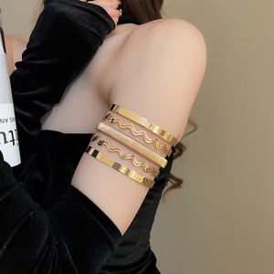 Detail of 5-piece gold cuff bracelet set with smooth wave and textured metal finishes