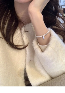 Detail of s925 silver LUCKY charm bracelet with freshwater pearls on a sweater