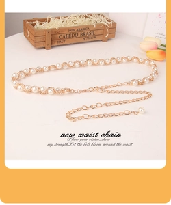 Macro detail of elegant golden metal chain intertwined with white faux pearls for dresses