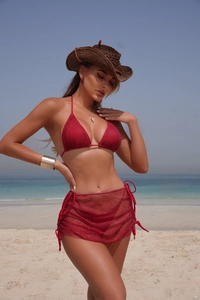 Détail d'un bikini rouge trois pièces avec jupe en résille à cordon sur la plage