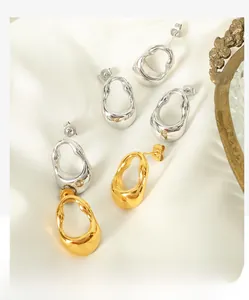 Detail shot of irregular gold and silver liquid metal earrings on white silk