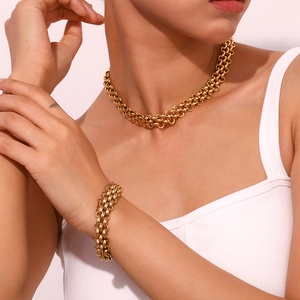 Macro detail of chunky gold triple-braided link necklace and bracelet set on model