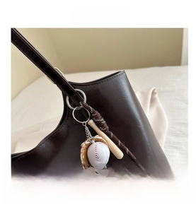 Detail of vintage tote bag with sports charms featuring a mini baseball and wooden bat