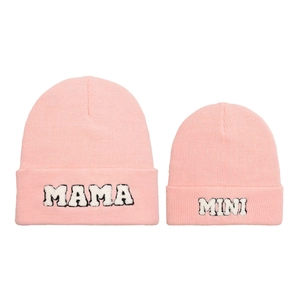 Dettaglio di berretti in maglia rosa con ricamo bianco MAMA e MINI per set famiglia