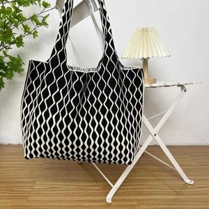 Detailed close-up of knitted tote bag featuring black and white geometric wave patterns